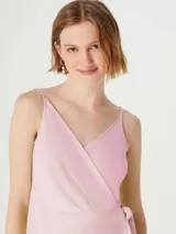 Vestido corto color amarillo pálido, con breteles finos, escote en V cruzado y lazo en la cintura.