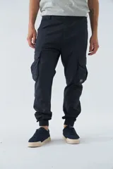 Pantalón cargo gris oscuro, corte slim, con cierre de botón y cremallera, trabillas para cinturón, bolsillos cargo con botón y puños ajustados.