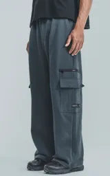 Pantalón de jogging gris oscuro de frisa con cintura y puños elásticos, bolsillos laterales, trasero y lateral con cierre.