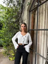 Blusa blanca crop con escote en V y volados, mangas largas acampanadas.