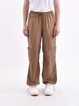 Pantalón marrón de corte ancho, con cintura elástica ajustable con cordón, bolsillos laterales y bolsillos tipo cargo en los muslos.