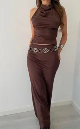 Conjunto de dos piezas color marrón oscuro, compuesto por un top halter con cuello drapeado y una falda larga ajustada.