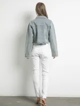 Campera de jean celeste con cuello clásico, cierre frontal con botones metálicos y dos bolsillos con solapa en el pecho. Está decorada con strass plateados en toda la superficie y tiene terminaciones desflecadas.