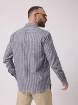 Camisa de manga larga a rayas verticales azules y blancas, con cuello abotonado y bolsillo en el pecho. Confeccionada en lino y algodón.