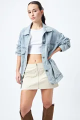 Minifalda color marrón claro, de corte recto con cierre metálico visible al frente y bolsillos decorativos con tachas.