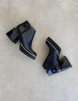 Botas cortas negras con textura de piel de serpiente y detalles en charol.