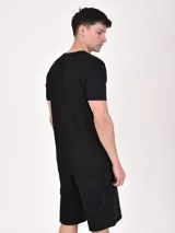 Remera negra de manga corta con estampado rectangular blanco con una palmera, una cabaña y la frase "RELAX TIME / FREE YOUR MIND".