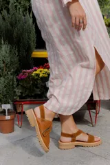 Sandalias de cuero color marrón y blanco, con suela track negra y ajuste con velcro.