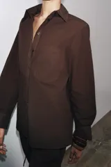 Camisa marrón de algodón con cuello solapa, manga larga con puños abotonados, bolsillo de parche en el pecho y cierre frontal con botones.