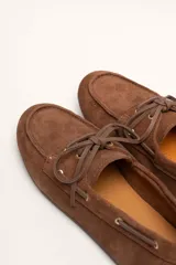 Mocasines náuticos de cuero color marrón, con cordones de cuero y suela de goma.