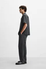 Pantalón negro de corte recto, confeccionado en tejido de mezcla de algodón y lino. Presenta cintura elástica, bolsillos laterales y traseros.