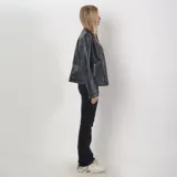 Campera negra de cuero sintético con cuello redondo, cierre frontal y bolsillos laterales con cierre.