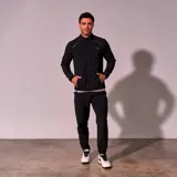 Chaqueta de entrenamiento color negro, sin capucha, con cierre frontal y detalles reflectantes.