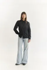 Camisa blanca de manga larga con cuello clásico y cierre frontal con botones. Presenta detalles de bordado calado a lo largo del frente.