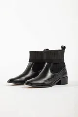 Bota negra con detalle de calcetín, diseño moderno y tacón bajo.