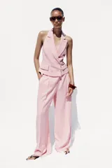 Pantalón ancho color rosa claro, de tiro alto con pinzas delanteras, bolsillos frontales y cierre frontal con cremallera y botones.