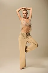 Pantalón de sarja color beige, tiro medio, de corte recto y pierna ancha, con apliques brillantes tipo joya en la parte delantera.