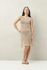Vestido de playa tejido a crochet color beige, sin mangas y con terminación de puntilla en el ruedo.