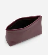 Neceser de poliuretano color borgoña, con forma trapezoidal y cierre de cremallera.