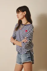 Remera de manga larga confeccionada en algodón a rayas horizontales azul marino y blanco. Tiene un pequeño bordado de corazón rojo en el frente y cuello redondo.