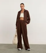 Pantalón de mujer color marrón oscuro, de corte recto y tiro alto, confeccionado en modal con poliéster y elastano. Presenta cintura elástica y un detalle de franja contrastante en las mangas de la chaqueta a juego.