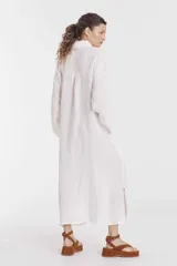 Vestido camisero largo color fucsia, de lino, con cuello camisero, mangas largas, cierre frontal con botones, bolsillos laterales y aberturas laterales en el ruedo.