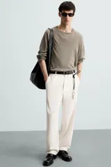 Pantalón de vestir color blanco hueso, de corte recto y tiro medio, con cintura elástica y cierre frontal de botón y cremallera. Presenta bolsillos frontales y bolsillos traseros de vivo.