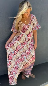 Vestido largo de seda con estampado paisley en tonos marrón, rojo oscuro y azul. Presenta escote en V y mangas cortas con volado.