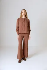 Pantalón de lino color beige, corte flare, tiro medio y costuras verticales al frente.