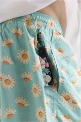 Short de baño celeste con estampado de margaritas amarillas y cordón ajustable en la cintura.