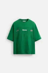 Camiseta verde con corte relaxed fit, cuello redondo y manga corta. Presenta una banda combinada con tejido de red en delantero y espalda, y estampaciones a contraste en el frente.