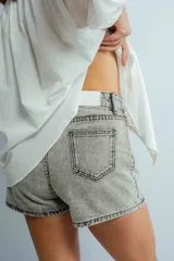 Short de jean gris claro con tiro medio, bolsillos delanteros y traseros, y cierre con botón y cremallera.
