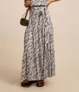 Pollera evasé long midi con traspase y lazo en el lateral, recorte fruncido en la parte baja y estampado de caracolas. Confeccionada en viscosa sostenible.
