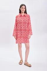 Vestido camisero corto de algodón con estampado geométrico en tonos rojo y blanco, cuello camisero, mangas largas y corte recto.