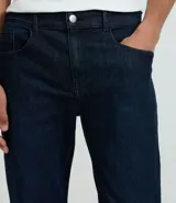 Pantalón slim fit confeccionado en tejido denim azul oscuro, con cintura con trabillas, cierre tradicional y bolsillos.