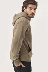 Buzo hoodie color arena con capucha, bolsillo tipo canguro y pequeño estampado en el pecho.