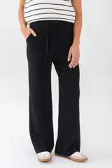 Pantalón tejido color blanco, de corte amplio y tiro alto, con bolsillos laterales y cintura con cordón ajustable.