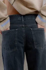 Pantalón jean de tiro medio color negro, corte mom, con bolsillos delanteros y traseros. Largo hasta el tobillo. Confeccionado en algodón 100%.