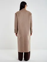 Tapado largo de corte oversize confeccionado en mezcla de lana. Presenta un diseño de doble botonadura frontal con botones oscuros, solapas de muesca y bolsillos laterales. Cuenta con interior acolchado y mangas forradas para mayor confort.