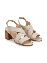Sandalia de cuero color beige y blanco, con taco de madera y hebilla metálica.