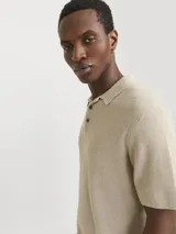 Polo de punto color beige con cuello clásico, mangas cortas y cierre con botones.