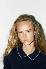 Top azul marino de punto con cuello solapa y manga corta. Detalle de acabados con vivos blancos a contraste en cuello y mangas.