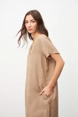Vestido color beige de lino, corte recto, con cuello en V y mangas cortas.