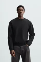 Sweater negro de punto con cuello redondo y mangas largas.
