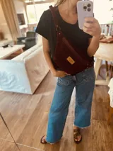 Riñonera de cuero color borgoña con correa ajustable.