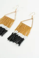 Par de aros colgantes con forma de triángulo dorado y flecos de canutillos en dorado, blanco y negro.