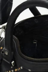 Cartera negra de cuero vacuno con correa desmontable, doble asa corta y cierre superior. Diseño matelassé con tachas metálicas plateadas y doradas en el frente y laterales con cierre.