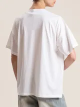 Remera blanca de algodón con cuello redondo y estampado negro con la frase "Très Chic" en el frente.