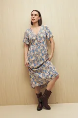 Vestido largo color verde oliva con estampado de hojas rosas, escote en V, botones al frente, mangas cortas y falda con leve vuelo.