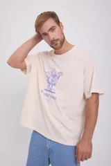Camiseta color crema de manga corta y cuello redondo con estampado de un personaje de caricatura en color violeta y texto "I told you".